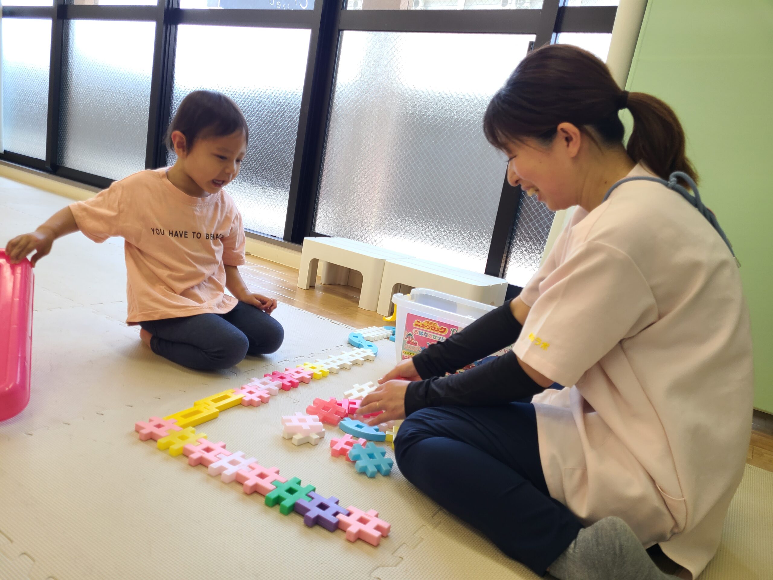 ブロックで知育療育をする児童指導員と子ども